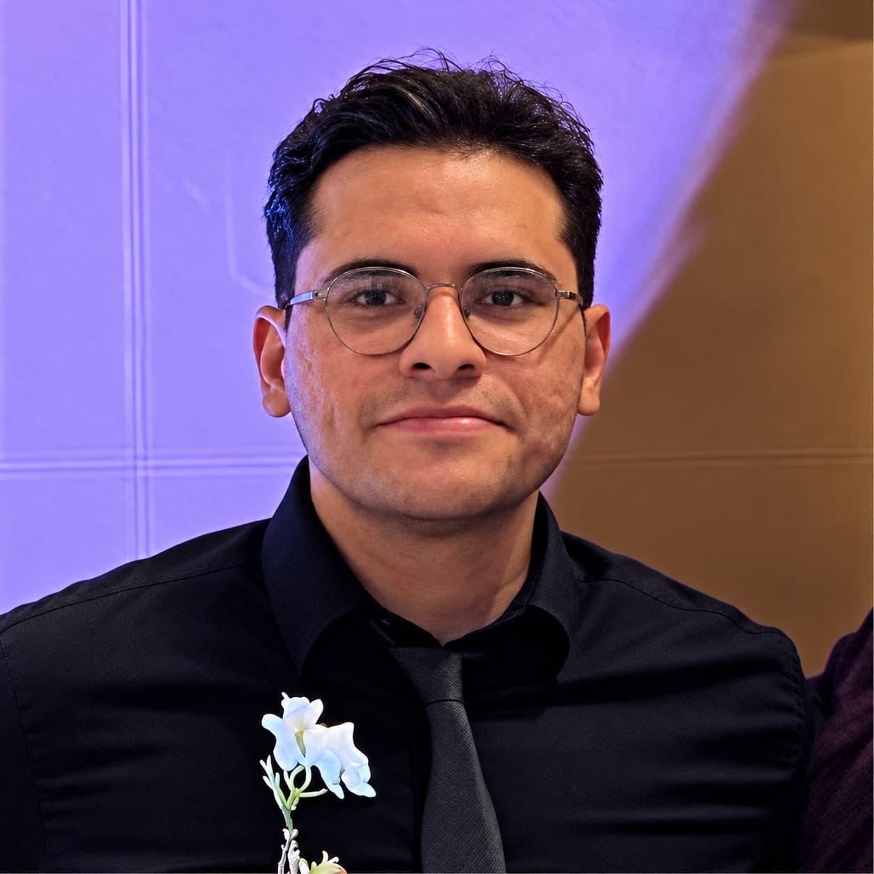 Aminreza Abbasi smiling, wearing glasses, a black shirt and tie